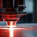 Precision laser cutting stainless steel in a workshop.
