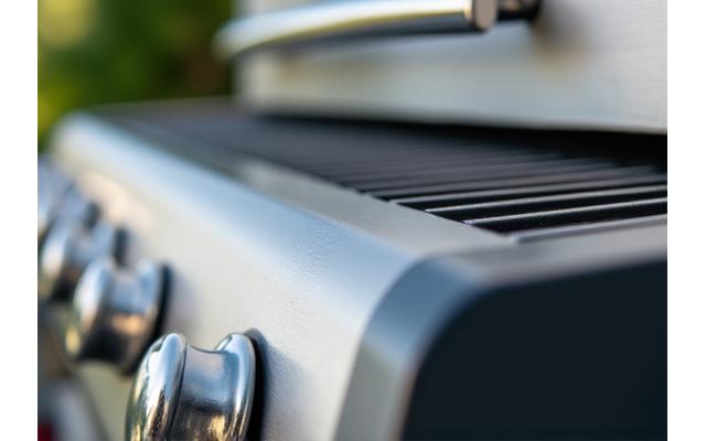 Modern outdoor grill made with low-impact, corrosion-resistant stainless steel, reflecting light.